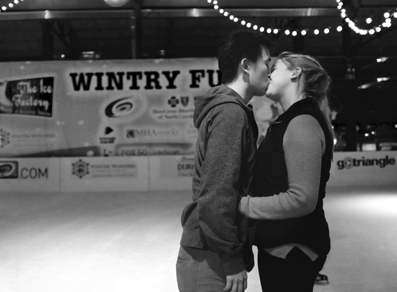 black and white photo of a young boy and girl at ice rink kissing