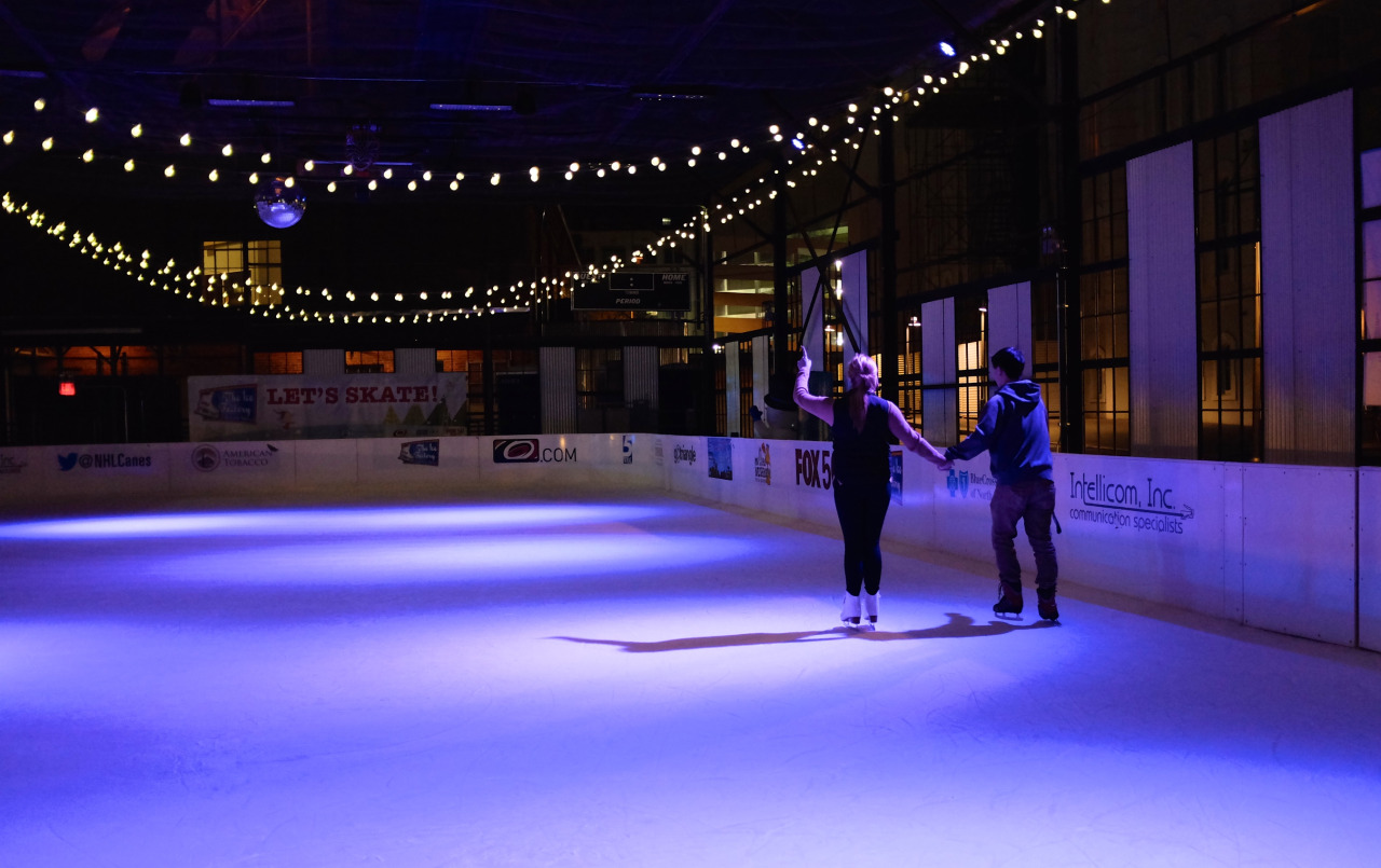 color photo of the young couple skating away from camera holding hands