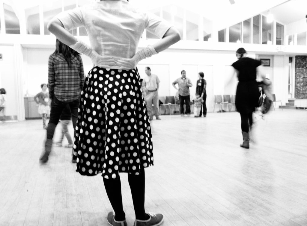 black and white photo at a country dance showing a girl in a polka dot dress from behind