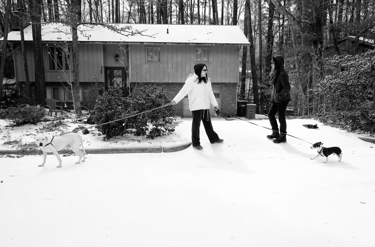 Black and white photo of two women outdoors walking a dog