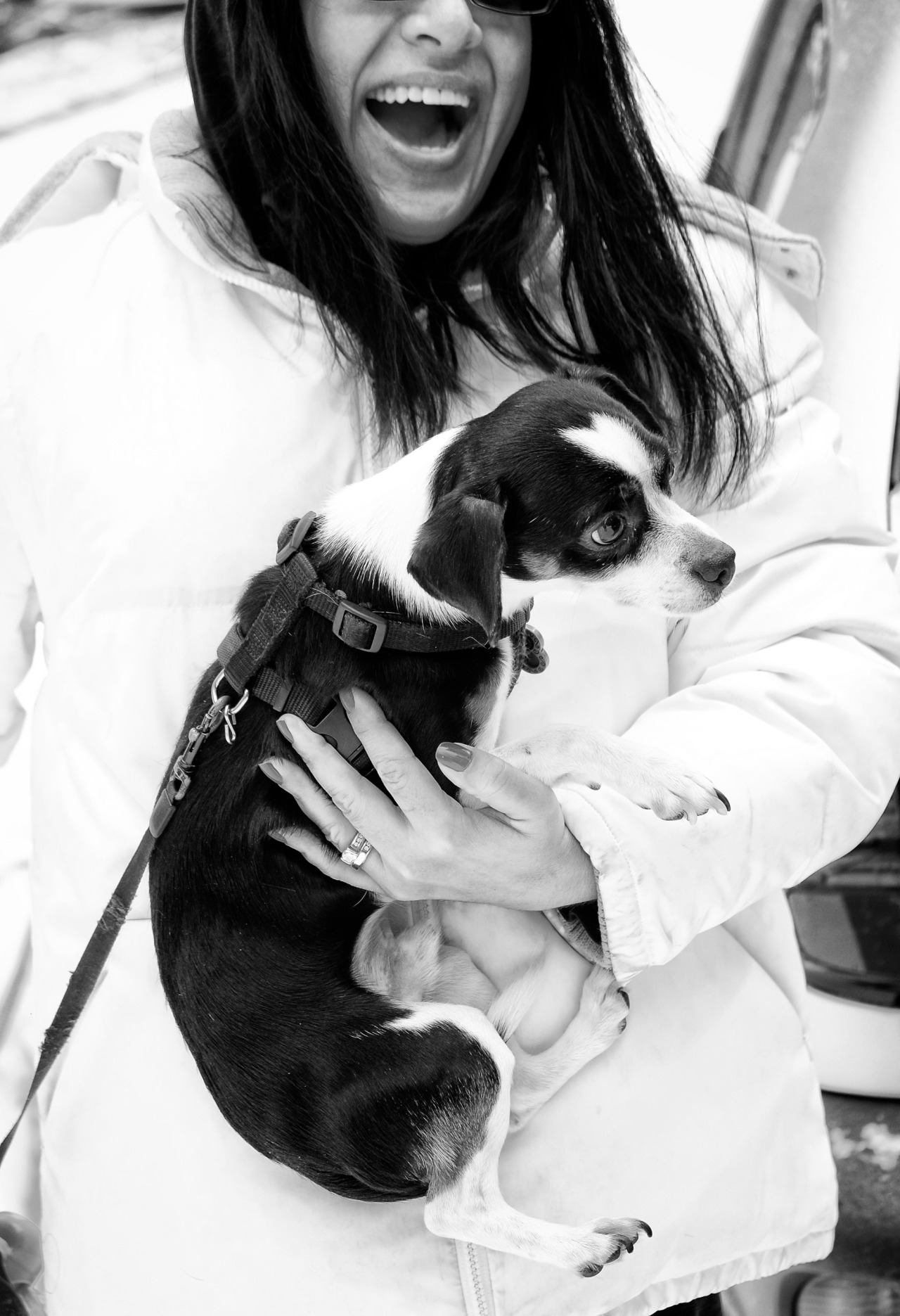 black and white photo of woman in white coat holding a black and white dog