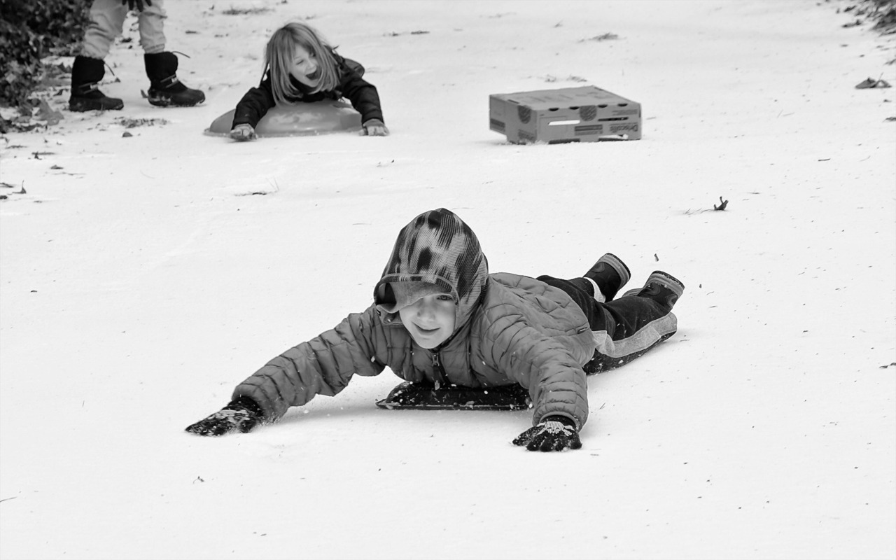 photo of child sliding in the snow