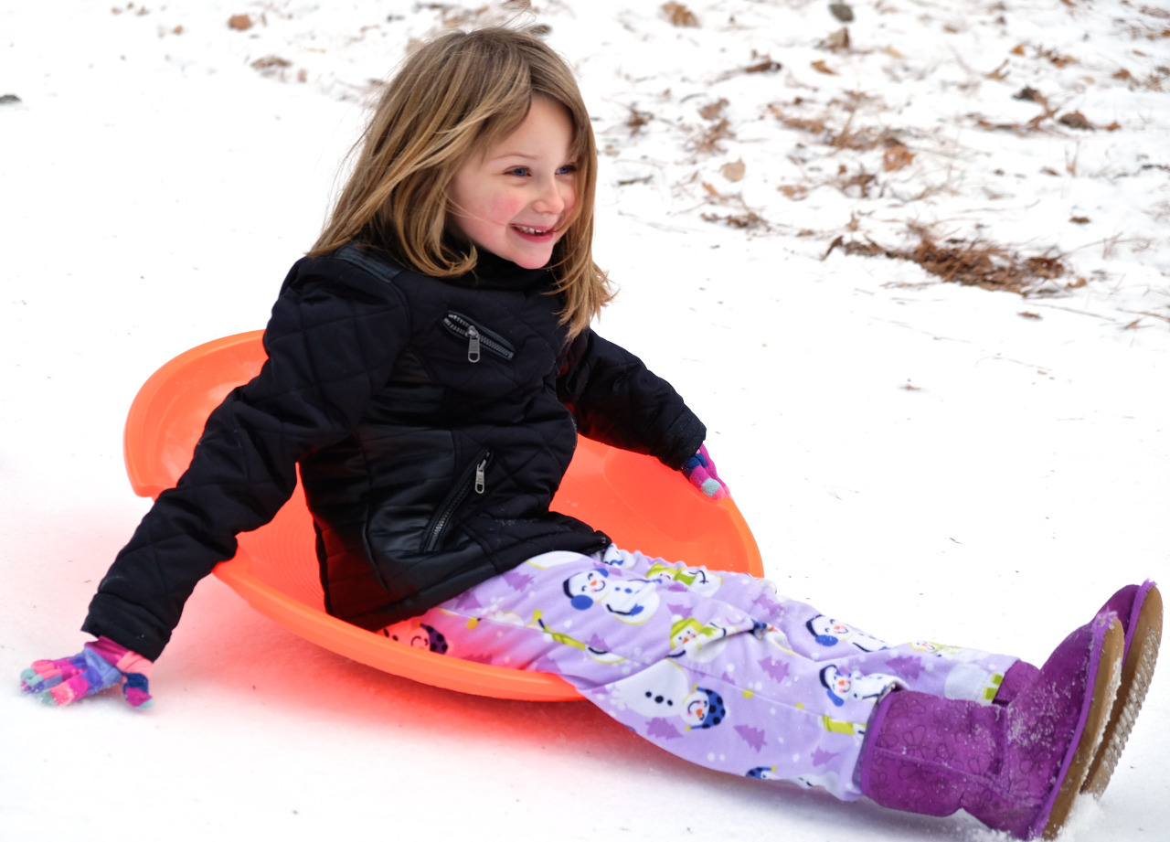 photo of child sliding in the snow