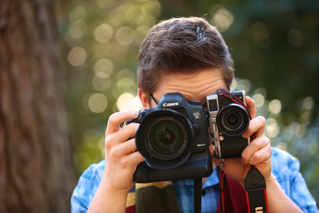 Colin Huth holding a large SLR camera and a small Fuji mirrorless camera