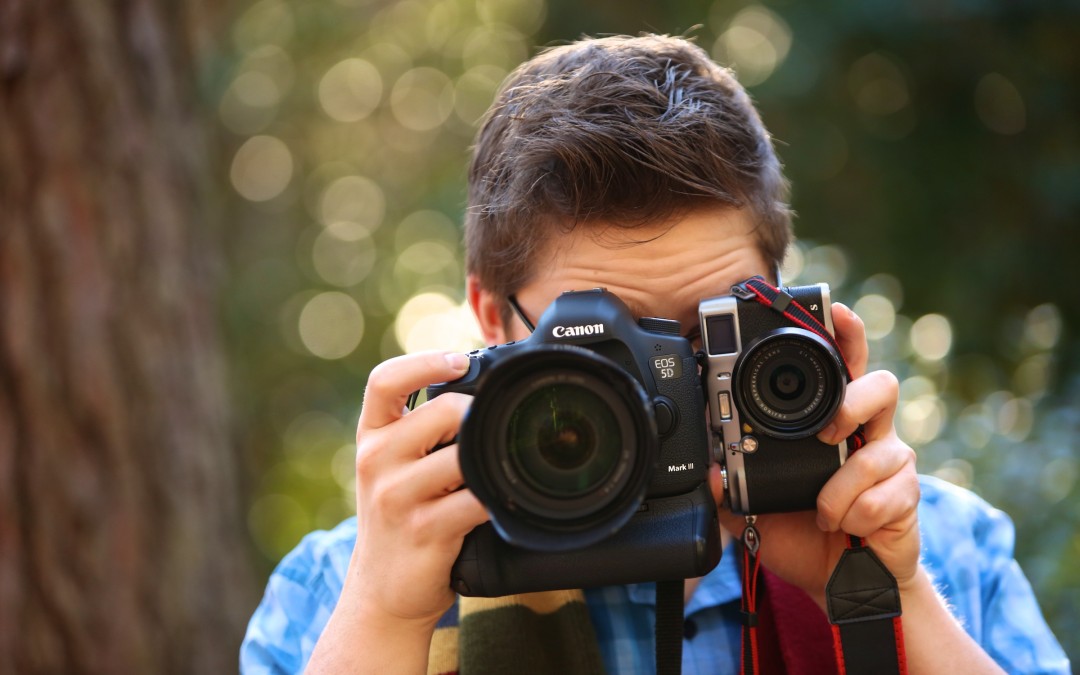 Colin Huth holding a large SLR camera and a small Fuji mirrorless camera