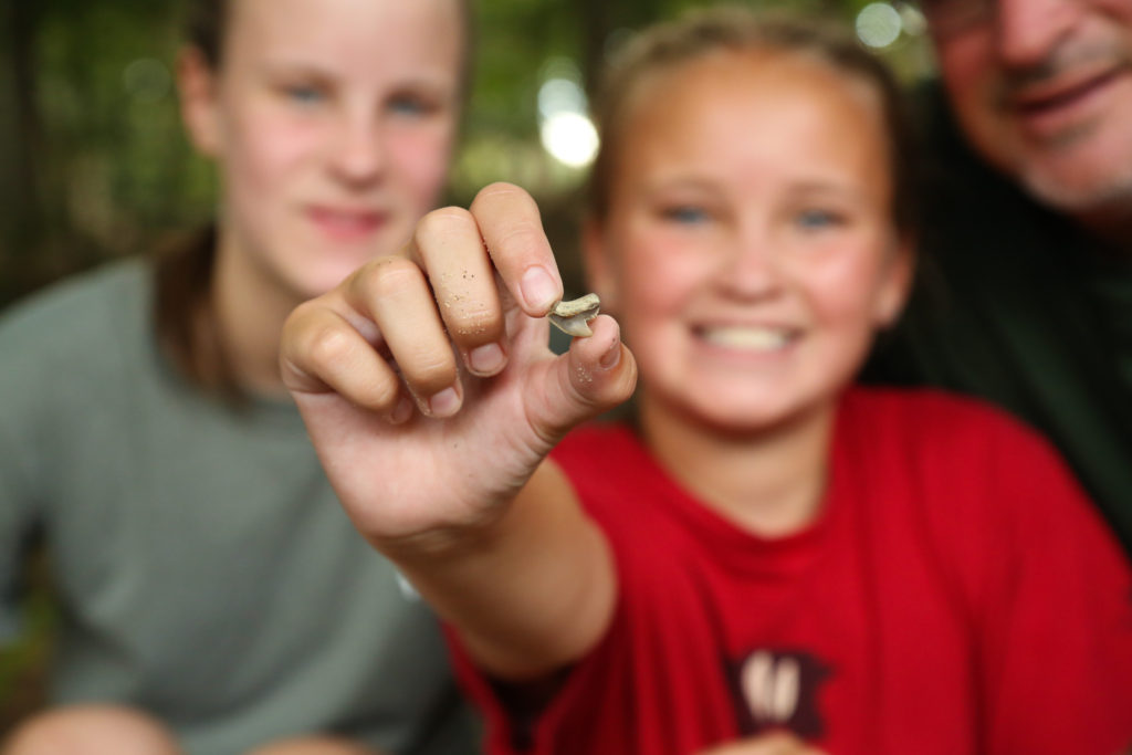photo of girl holding a fossil toward the camera