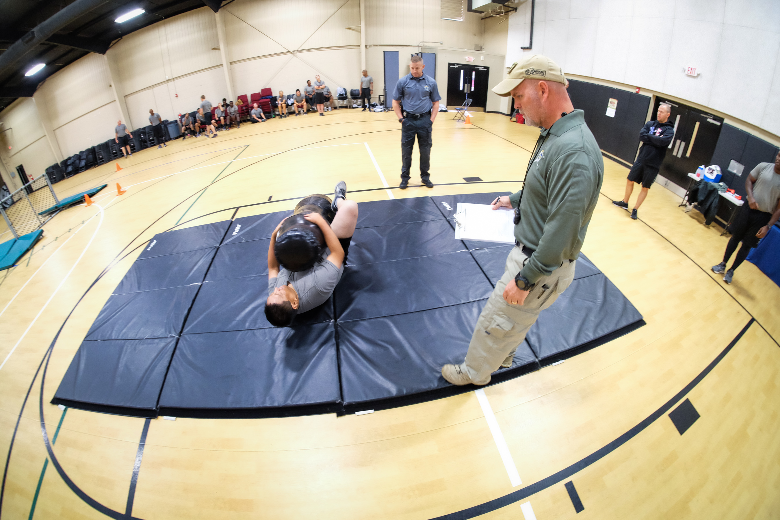 Deputy recruit rolling a heavy bag on a mat in a gym