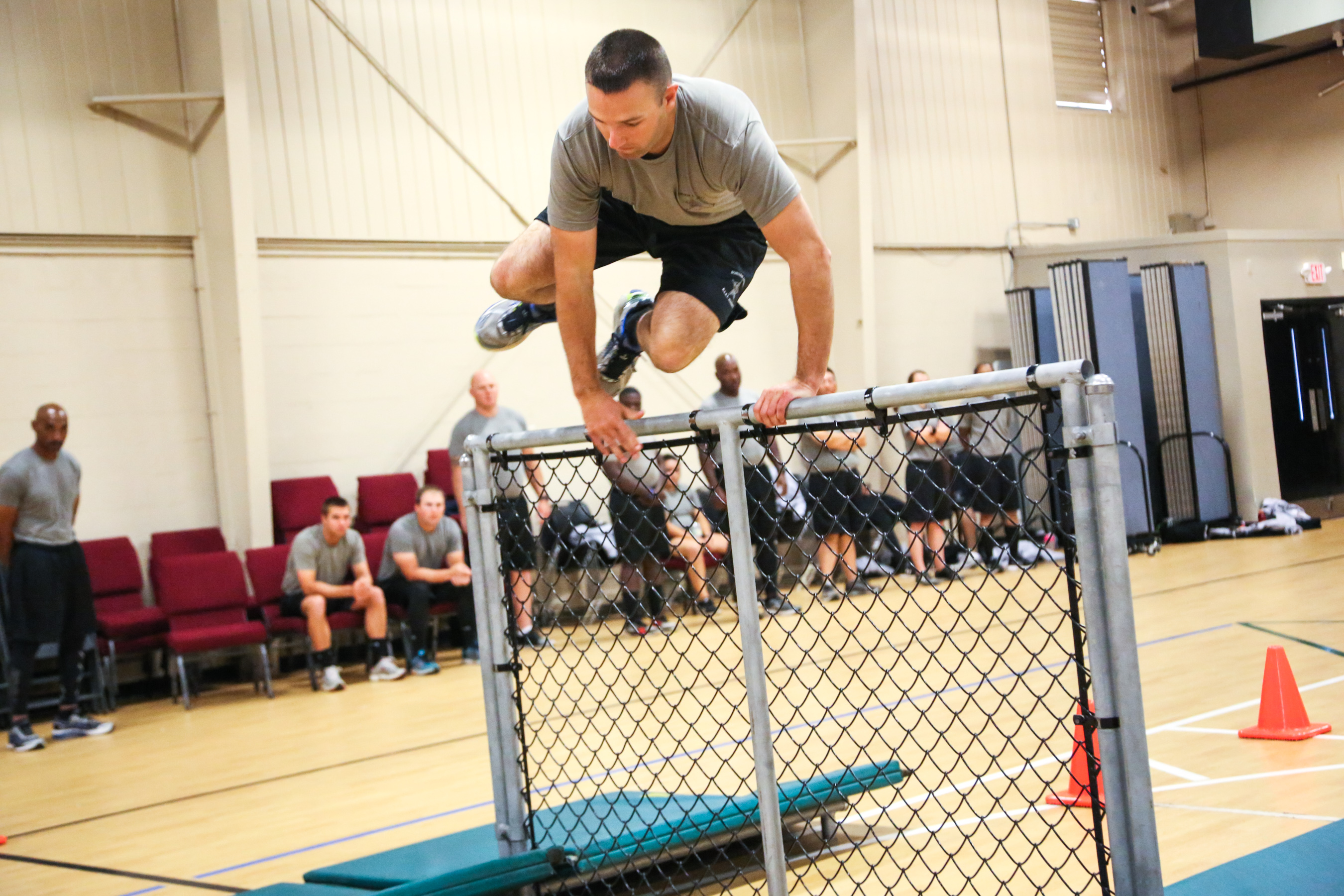 Deputy recruit leaping over a piece of fence in a gym
