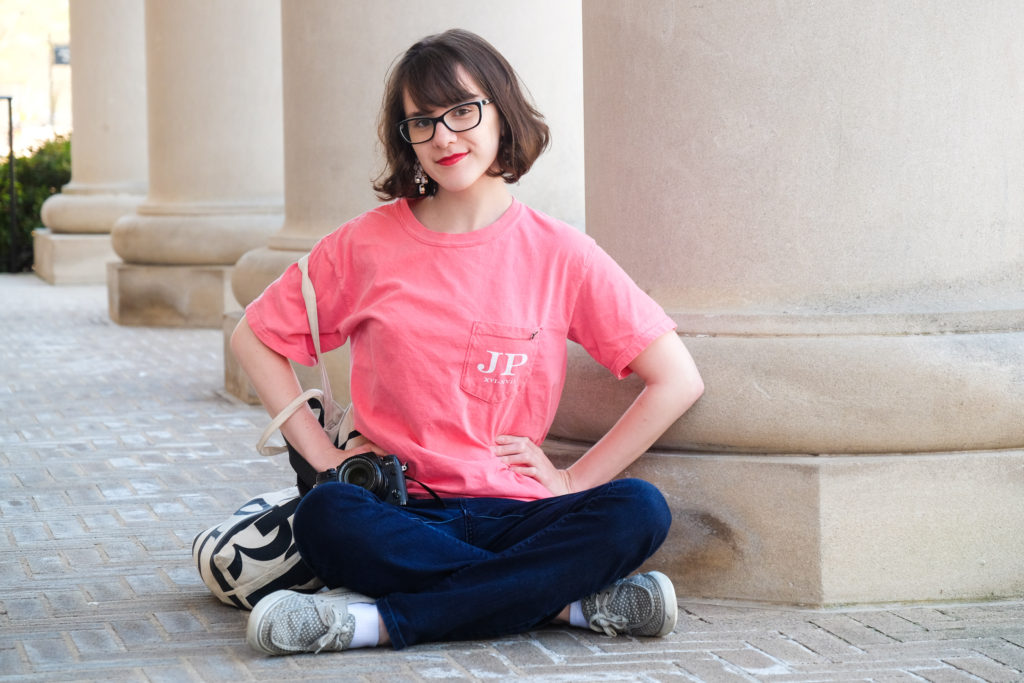 Teen girl in pink shirt with large building columns behind her