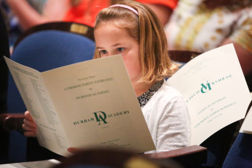 Photo of a young girl reading the DA Graduation program