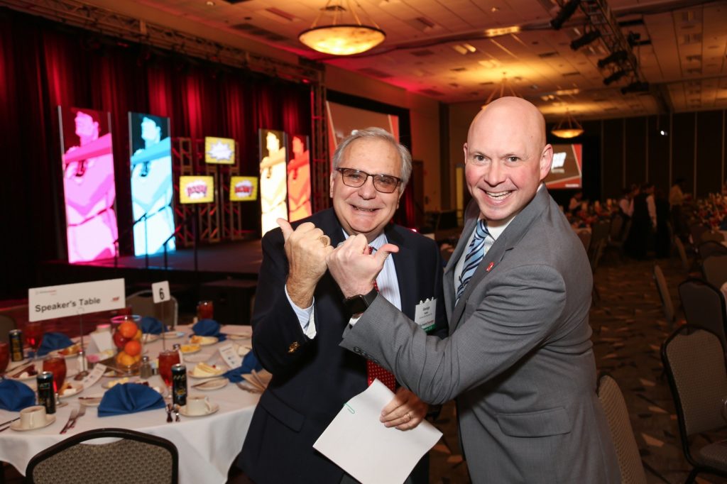 Two businessmen make a bull horn sign with their hands