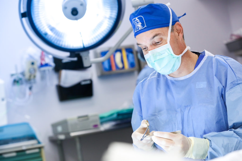 close shot of a doctor in the OR wearing a Duke logo surgery cap