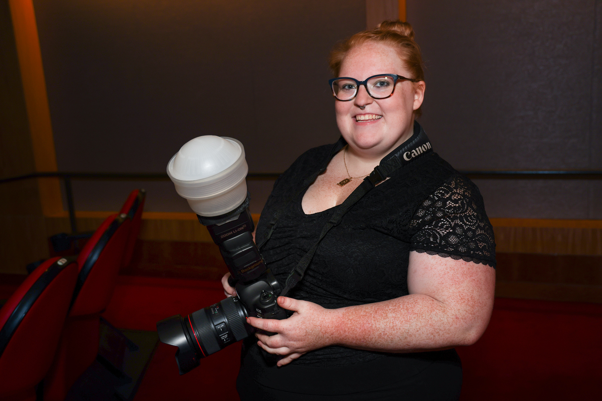 photo of a young female photographer with red hair holding a camera with flash
