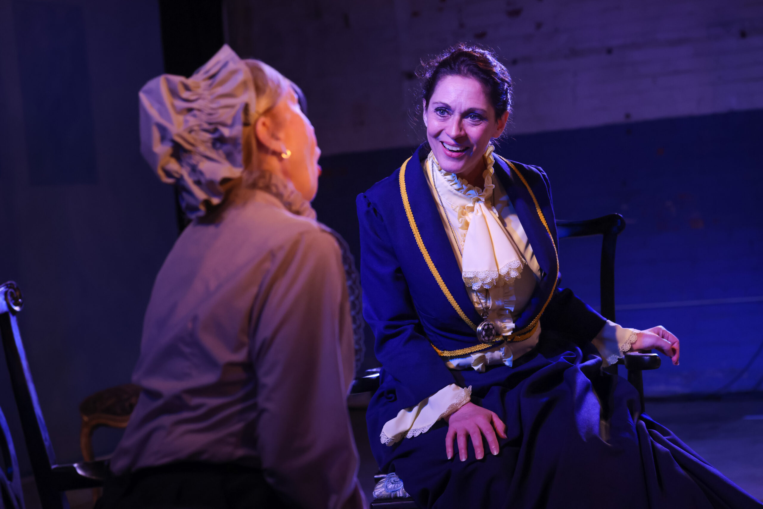 magenta theatre lighting with a young female actor glaring at another actor with her back to the camera