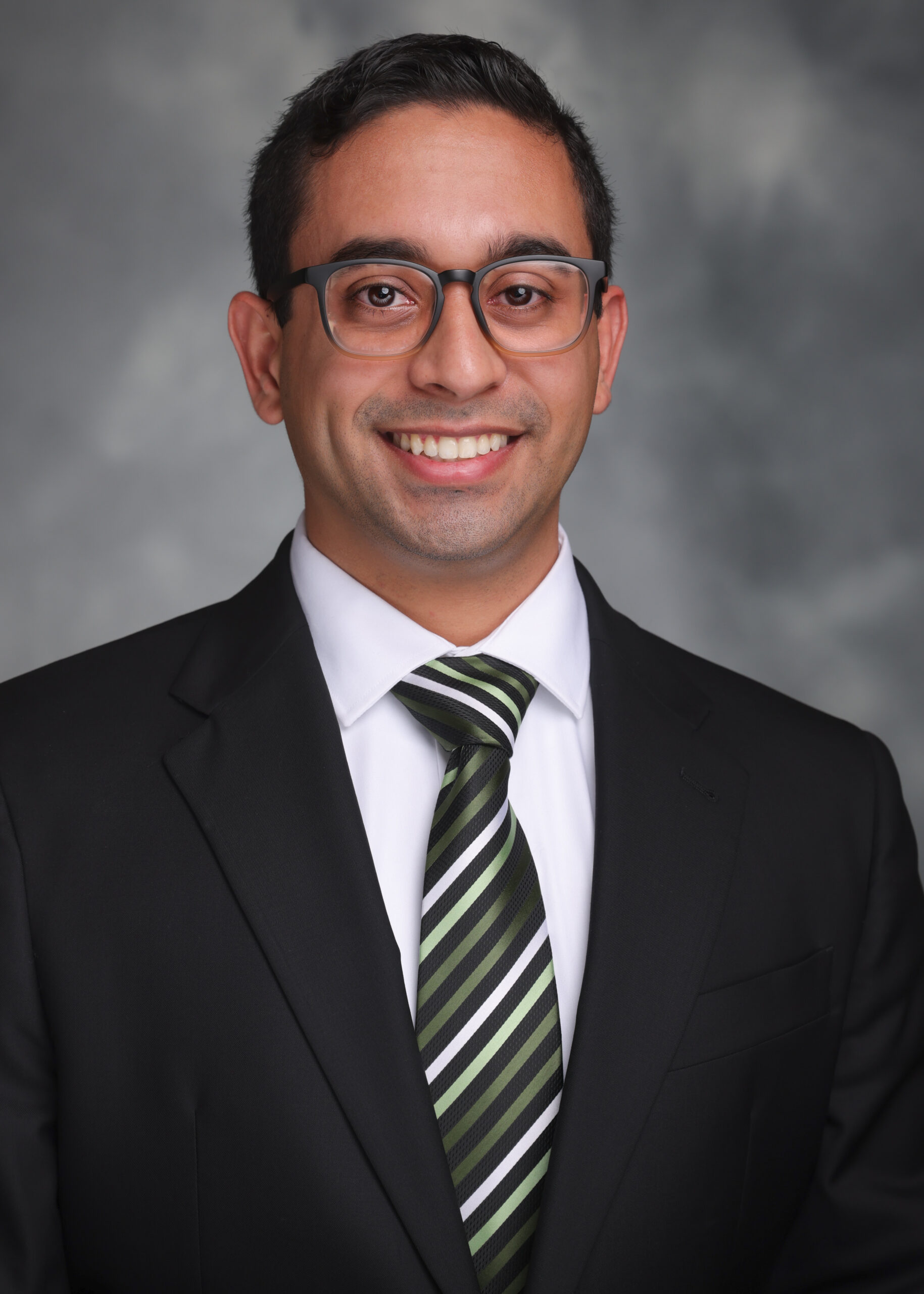 portrait of a man smiling at the camera with a nice mottled gray background