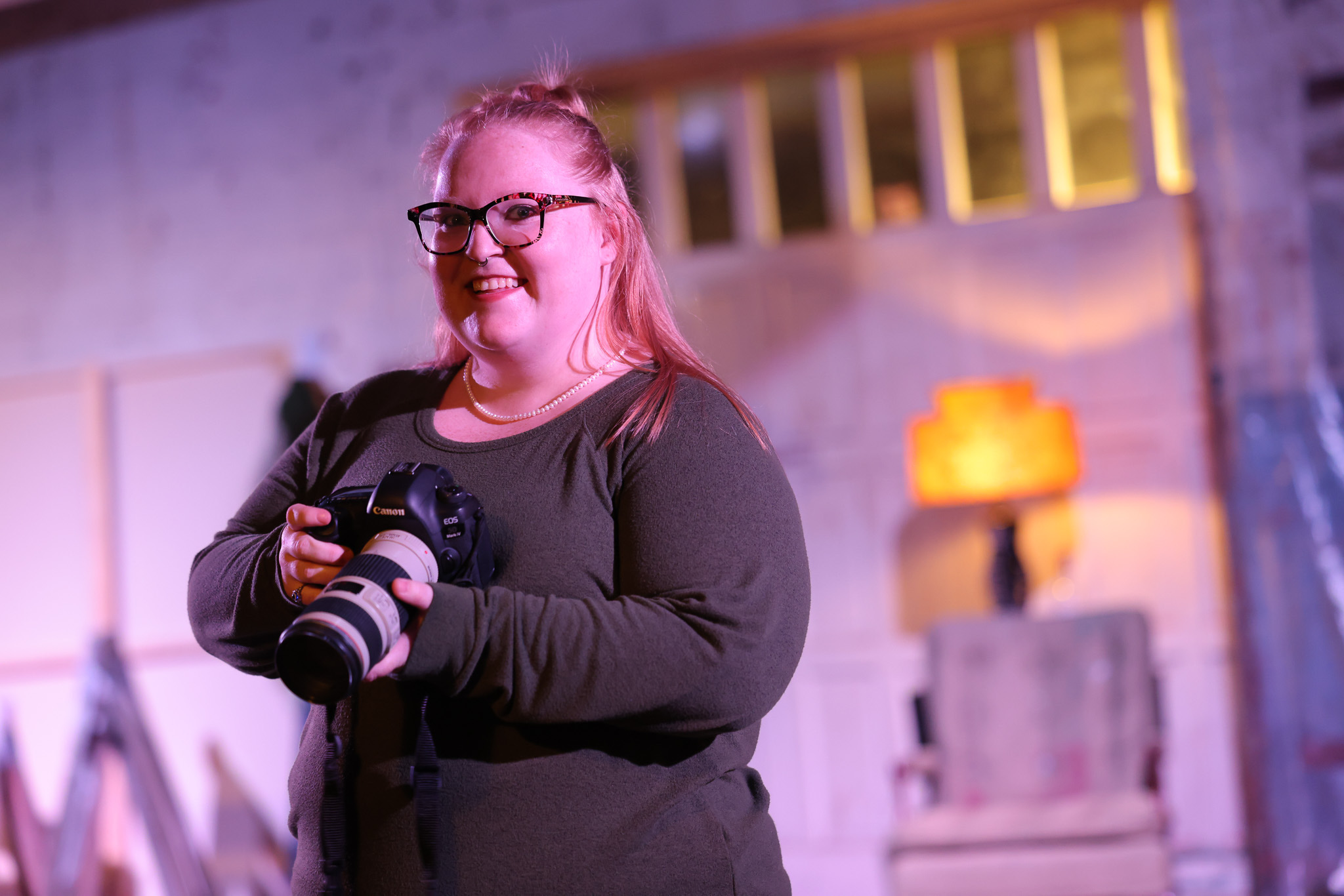 36C29620-0140-4140-9D7C-BA14ACDB1953 photo of a young female photographer with red hair holding a camera with flash