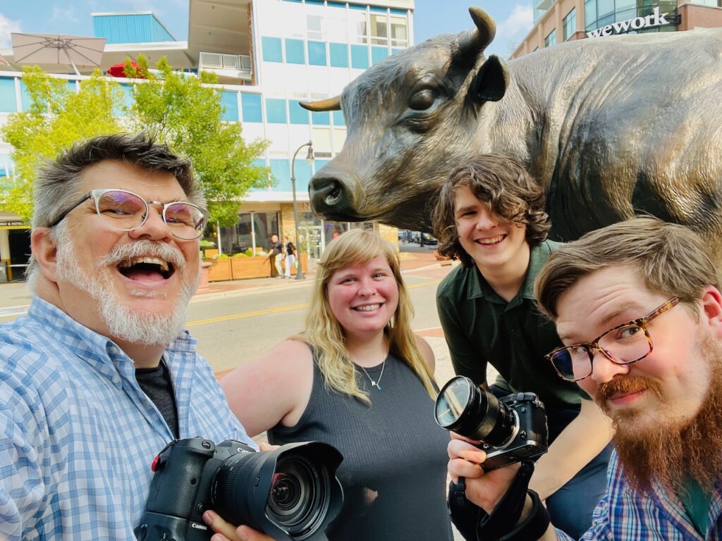 4 smiling people around a statue of "Major the Bull' on a sunny day (in photo Ken, Colin and Oliver Huth with Lizzie Potter)