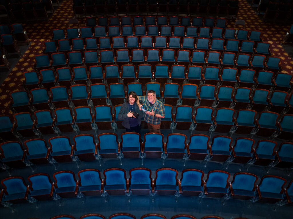 overhead image taken by drone of Ken & Oliver Huth in a sea of blue theatre seats at the historic Carolina Theater Durham