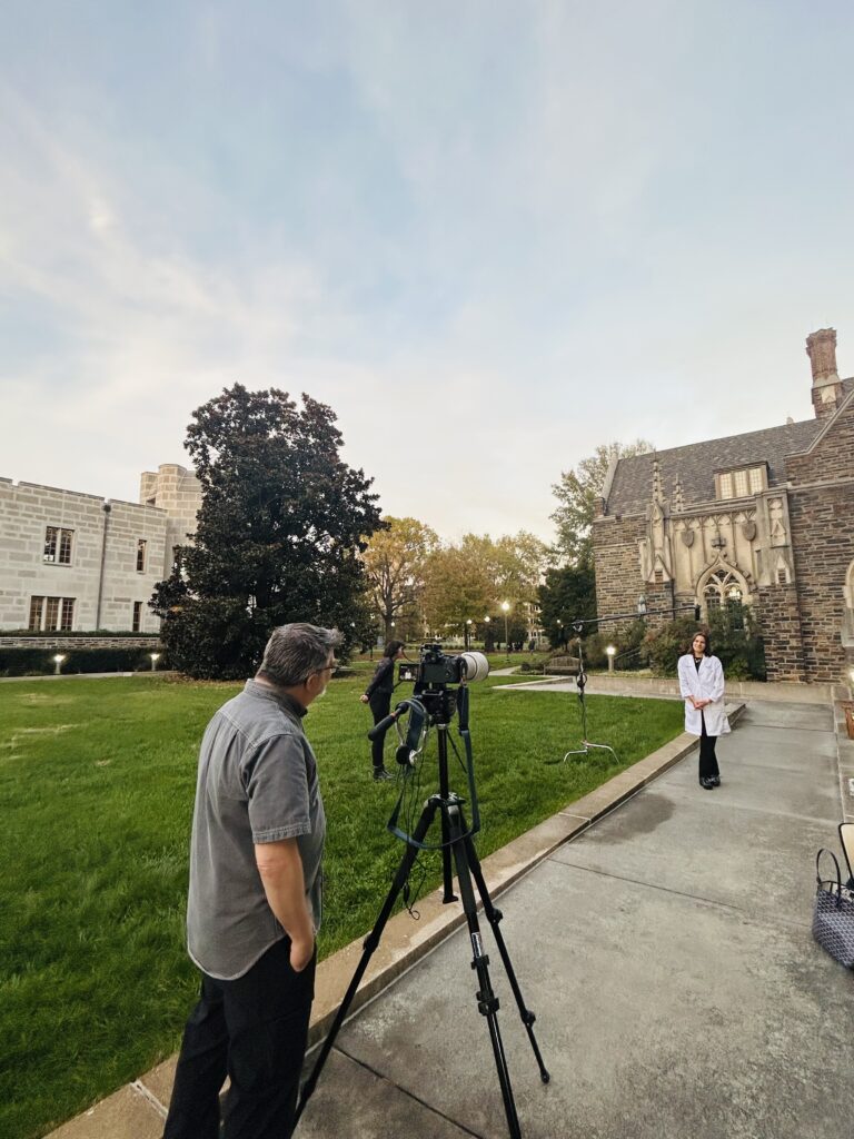 a video recording session with Ken Huth behind a video camera and an assistant with a second camera and boom microphone recording a medical Trainee