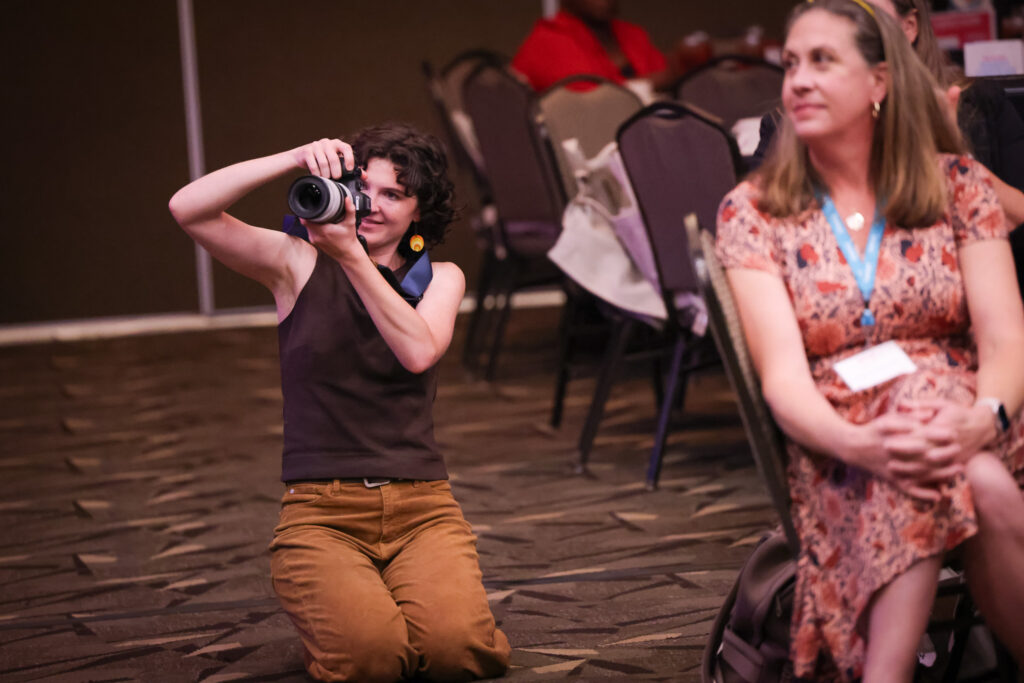 photographer Erin Scannell kneels at a lunch event to capture a photo
