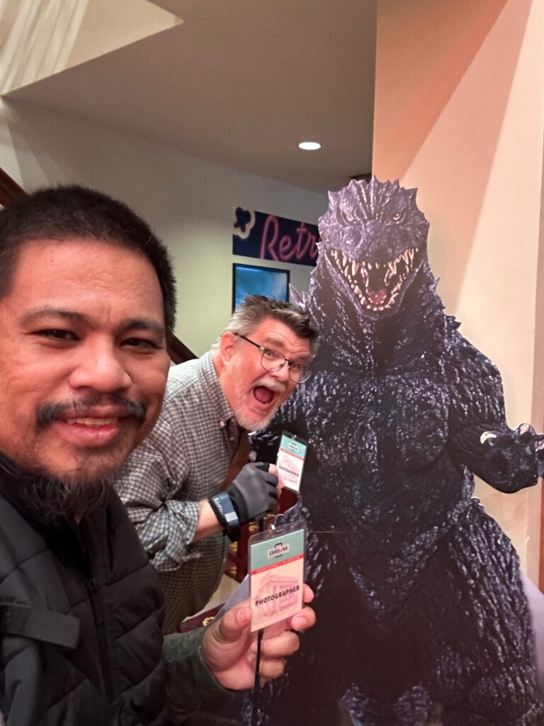 Rajha Tahir, Ken Huth and Godzilla large cut out picture. They hold press badges for Carolina Theatre