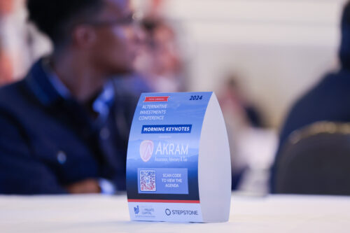 sponsor table tent display at an event with blurry business people looking on behind.