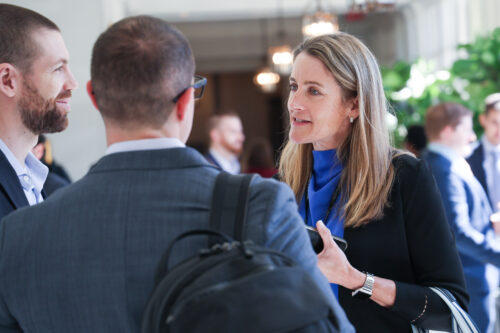 business woman speaks using hands with two young business men at a conference