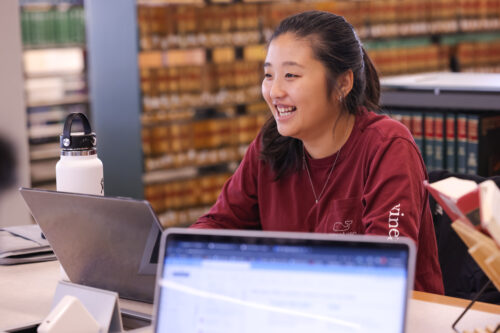 image of a college age woman in a university library smiling