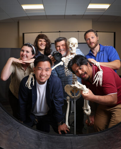 group of photographers making faces with a skeleton in the group.
