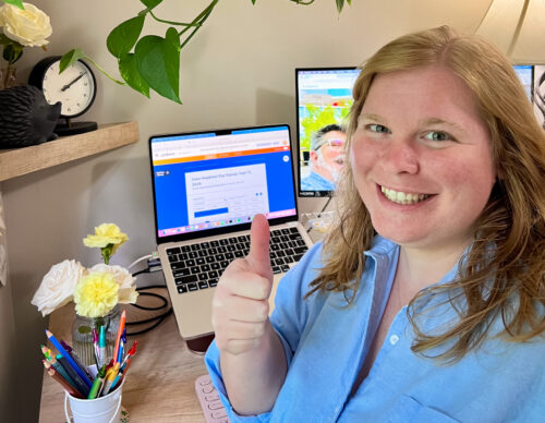 portrait of Lizzie Potter at her desk with computers and flowers